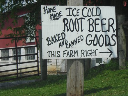 white homemade sign on telephone pole selling ice cold root beer and baked goods