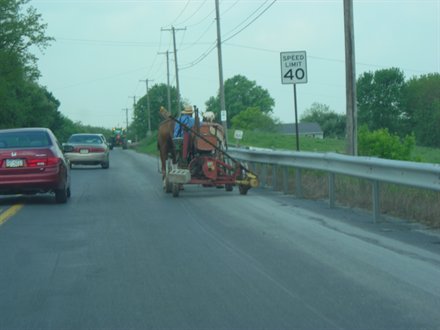 amish man driving farm equipment on the side of a road in lancaster