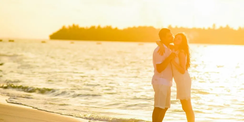 couple kissing, with sunset and beach in background