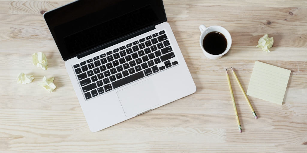 laptop on wooden desk with coffee and pencils