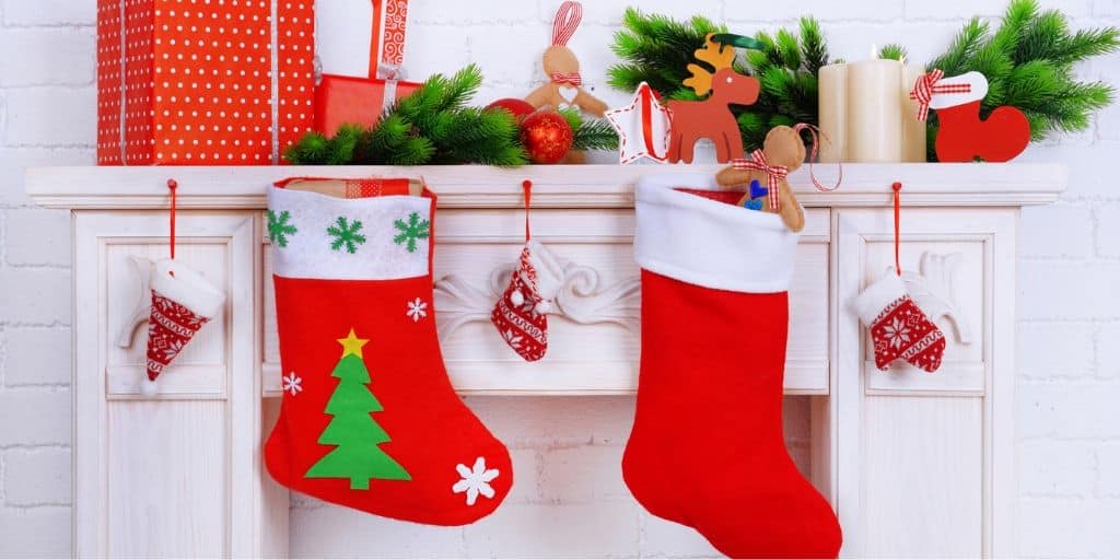 white fireplace with mantel, and two Christmas stockings for men hanging
