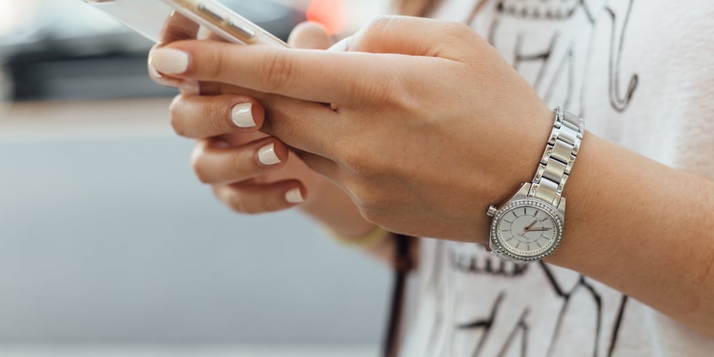 woman with manicured nails holding an iphone, texting