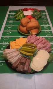 three DIY Superbowl Party trays with veggies, dips, sandwich fixings, on top of a homemade football field cloth