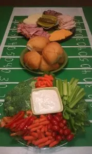 three DIY Superbowl Party trays with veggies, dips, sandwich fixings, on top of a homemade football field cloth