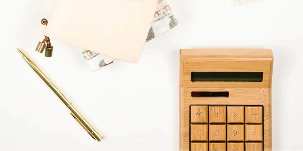 white desktop with wooden calculator and pen/notepad