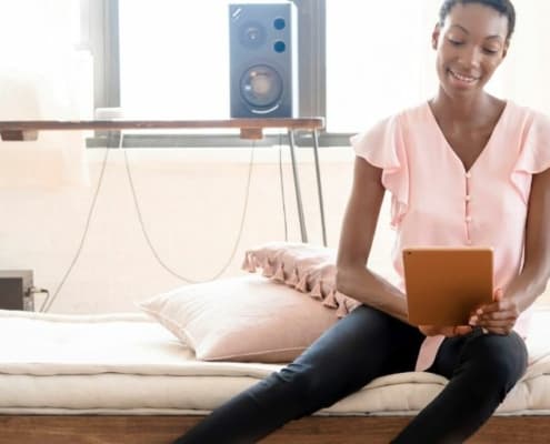 woman looking at iPad, smiling, thinking about meeting her financial New Year's resolutions