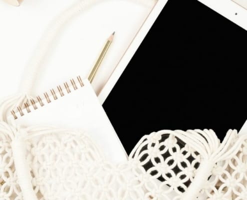 iPad with notepad, on white desk, in white crochet bag