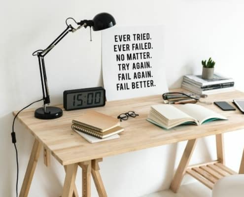 wooden desk with reading lamp and inspirational poster