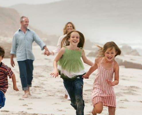 young family running on beach during early retirement
