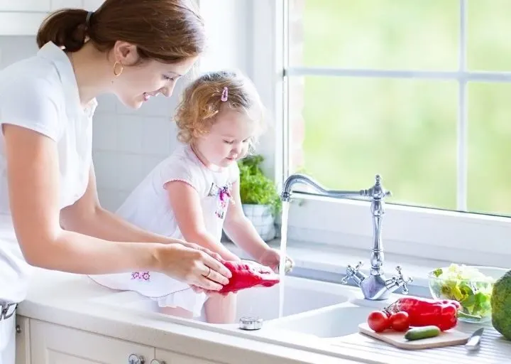 woman with toddler, using water at kitchen sink, looking for ways to save money on water bill