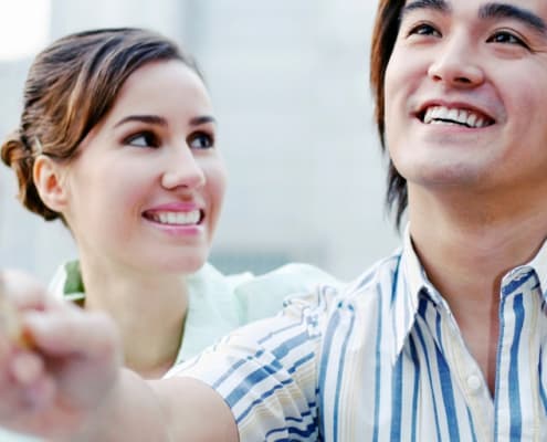 young couple, asian male handing over credit card to banker