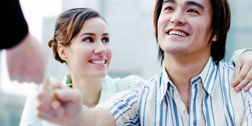 young couple, asian male handing over credit card to banker