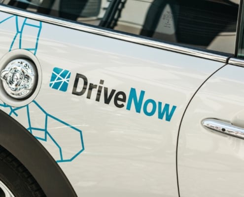 white car with car advertisement wrapping "Drive Now"