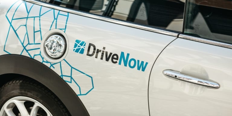 white car with car advertisement wrapping "Drive Now"
