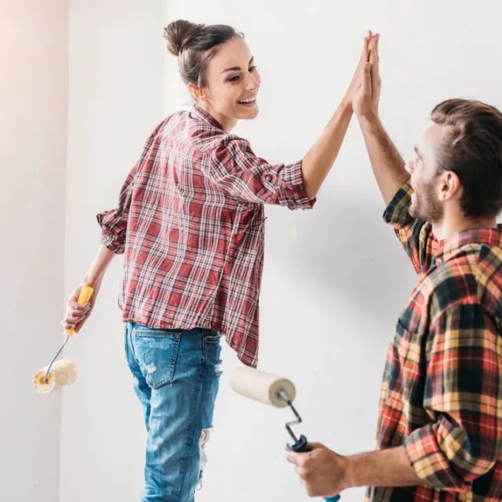 a young couple painting their new wall and slapping each other five