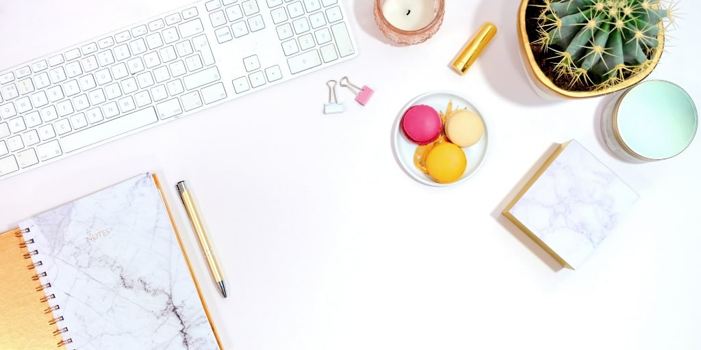 white desk, white keyboard, colorful macaroons, plant, notepad