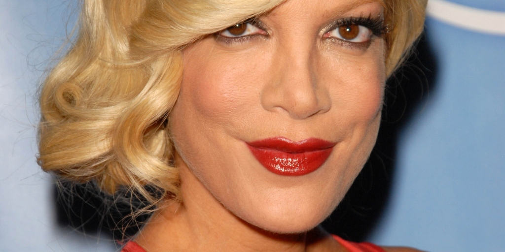 tori spelling with bun on side, red lipstick, blue background