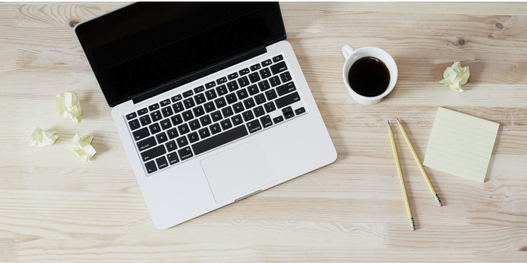 laptop on wooden desktop, with coffee and pencils