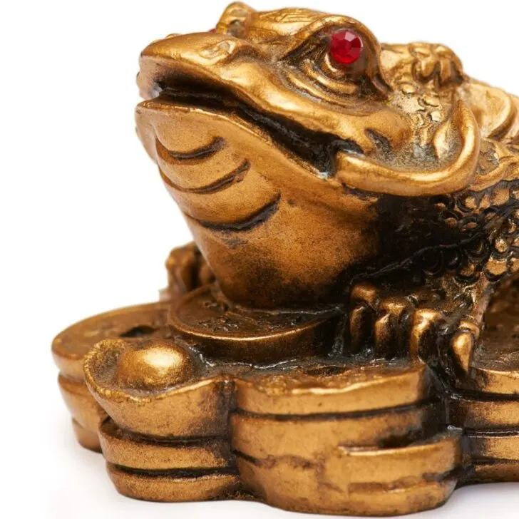 golden frog with red eyes on top of lots of gold coins