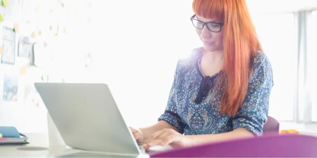 young woman with glasses on laptop, working on money arbitrage