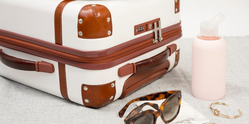 white luggage with leather accessories, sunglasses, bottle of water, to be used with free airline tickets