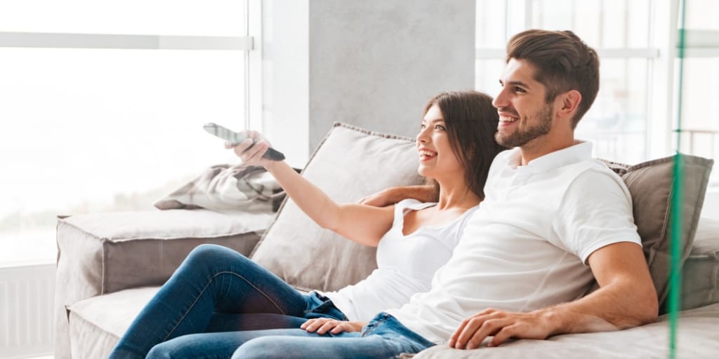 couple sitting on couch with tv remote