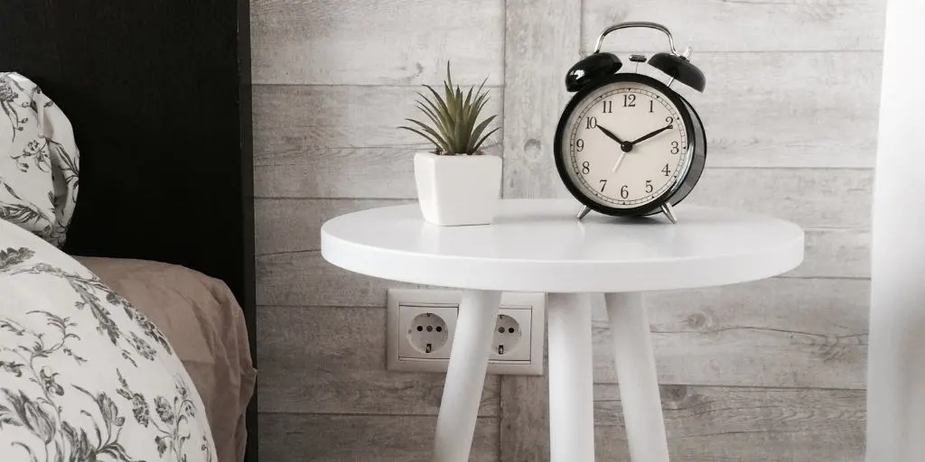 white bedside table with old fashioned clock and succulent plant