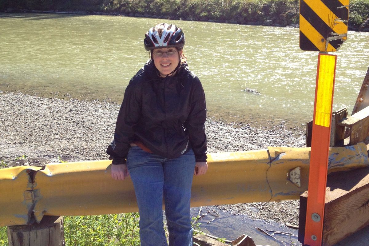 author in Alaska smiling with river in background