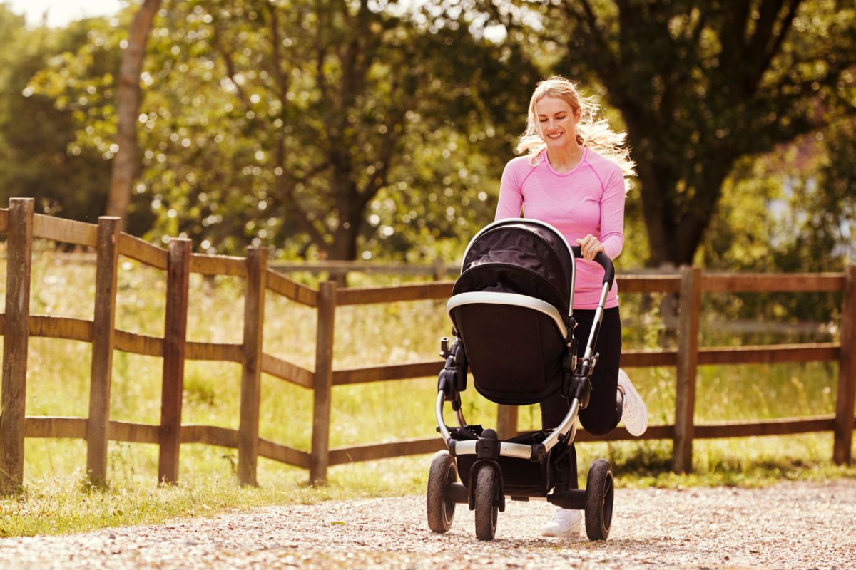 woman in pink shirt smiling into stroller, walking with fitbit