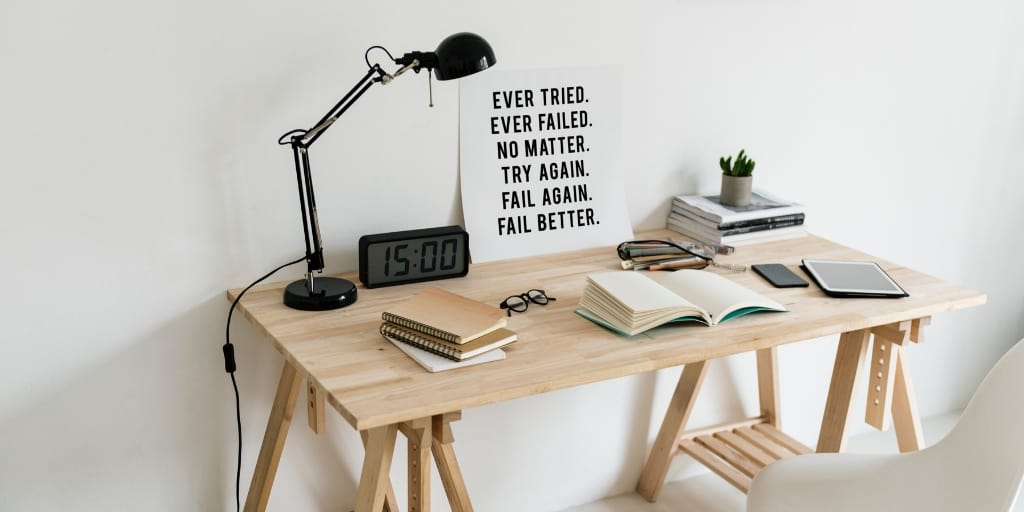 wooden desktop with lamp and motivational poster