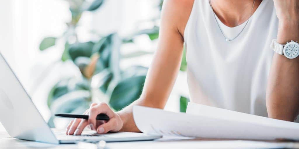 woman in white sleeveless shirt working at a laptop