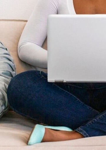 woman on couch with laptop, working on financial wellness reflection questions