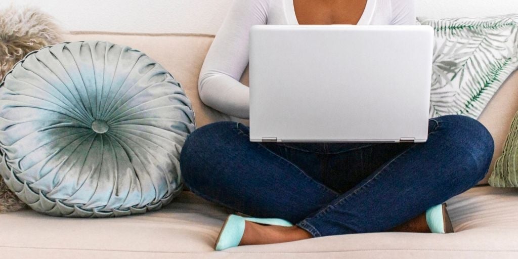 woman on couch with laptop, working on financial wellness reflection questions
