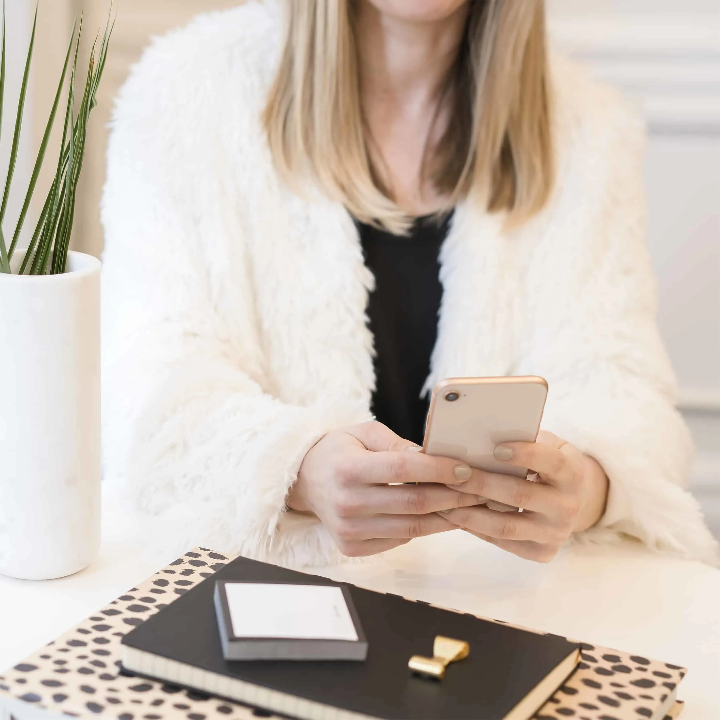 woman on her phone, sitting at desk, with leopard notepad