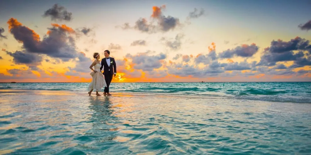 A bride and groom, walking along the beach and talking about marriage and finances