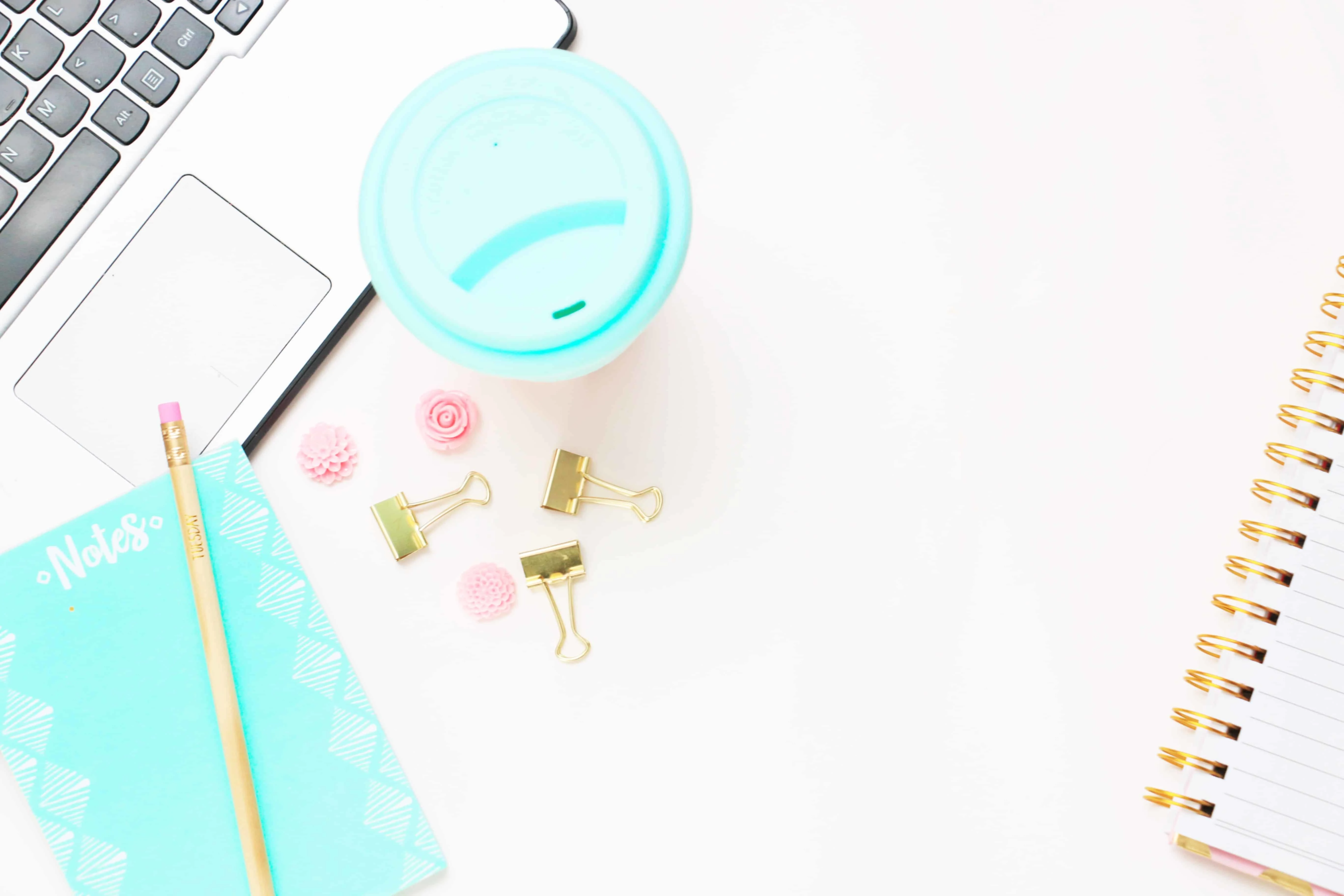 coffee with a light blue lid on a desk, with a laptop, and binder clips