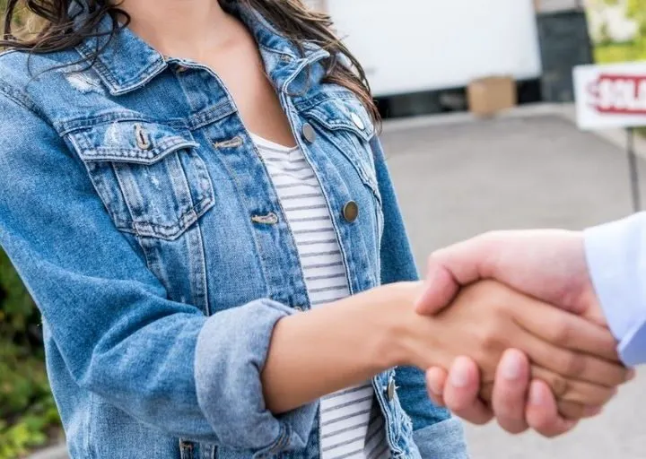 woman in jean jacket shaking hand of man she's collecting old washer scrap from for extra cash