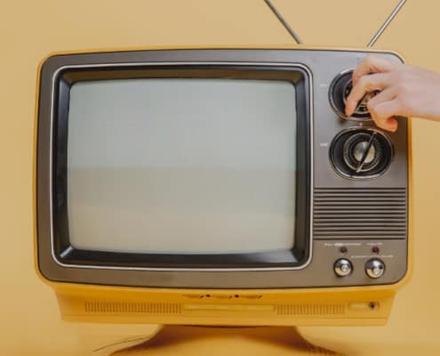 vintage television on yellow background, someone turning it on