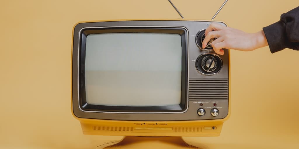 vintage television on yellow background, someone turning it on