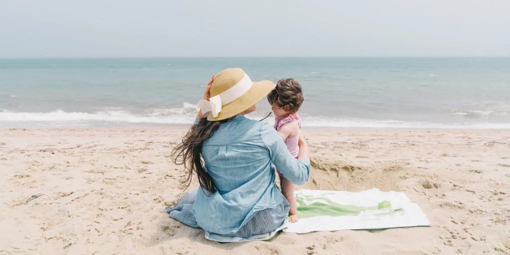 mother with child on beach, thinking about time vs money