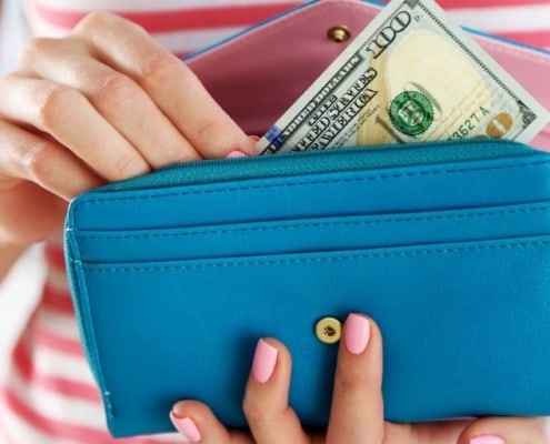woman in red striped shirt with wallet of money, reading budgeting tips for beginners