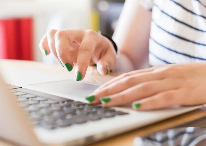 woman hands typing with green nail polish, looking for programs that match your savings