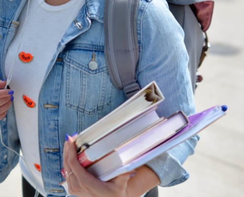 student holding textbooks and walking to class