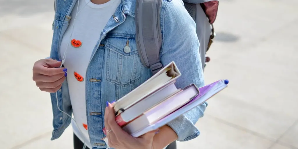 student holding textbooks and walking to class