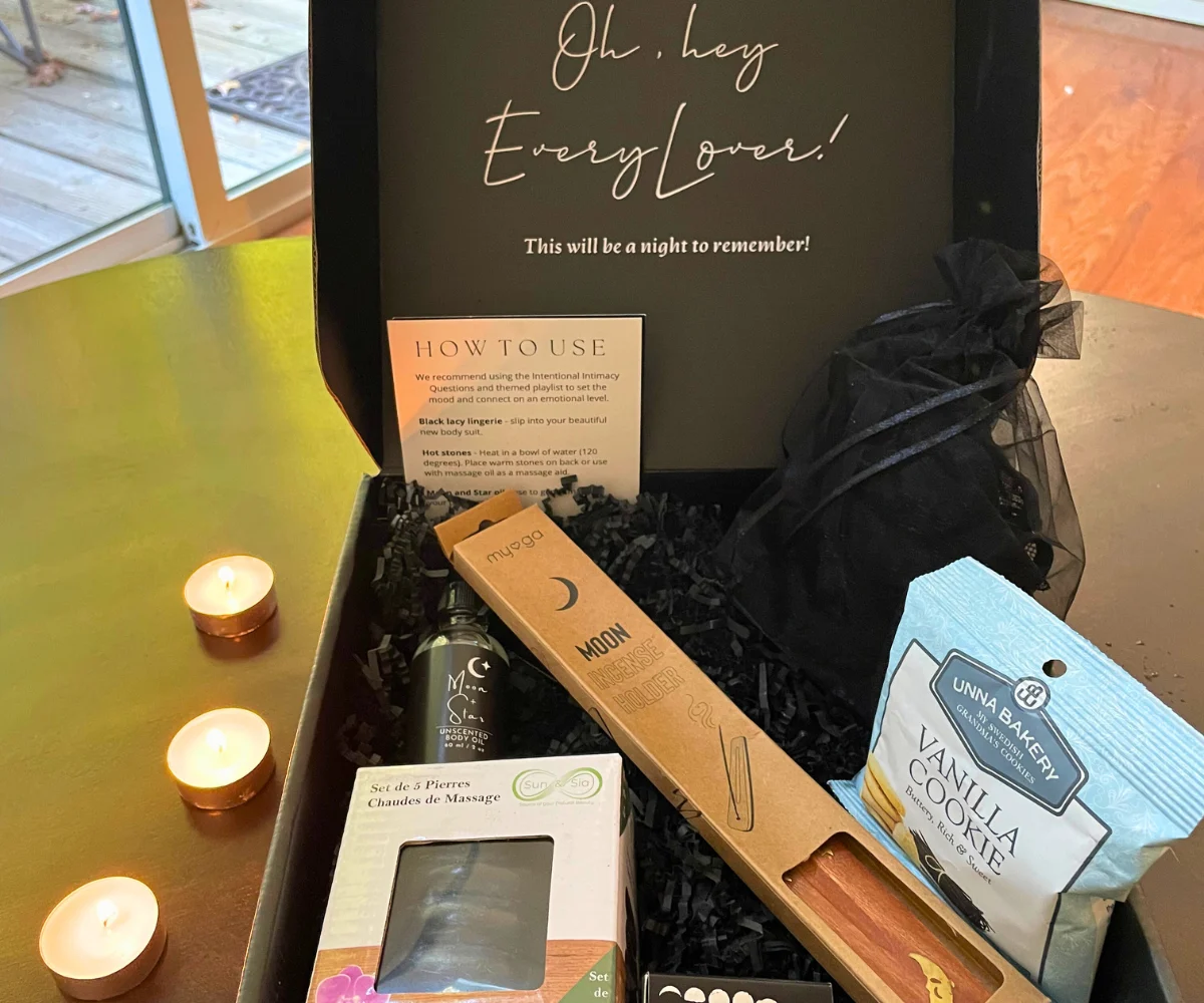 black box opened to show massage stones, incense holder, massage oil, intimate wear for a woman, etc.