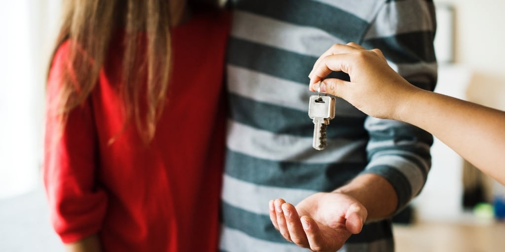 realtor handing keys to couple for their first home