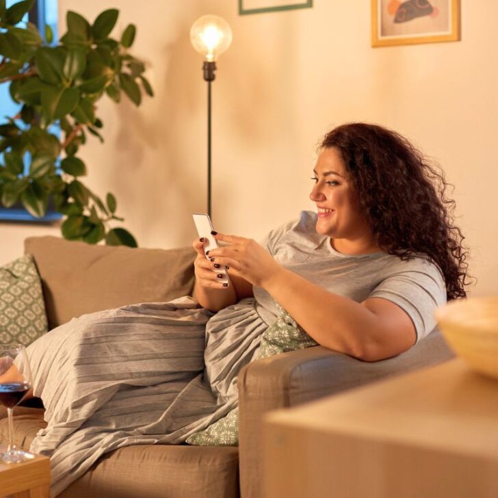 woman on cozy couch with phone, smiling, earning extra cash