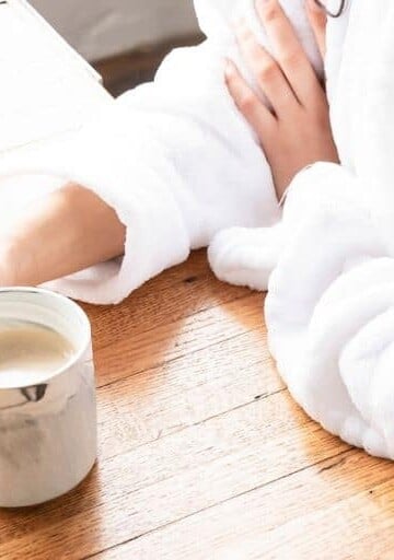 woman in robe at home with coffee mug, wondering can furloughed employees file for unemployment