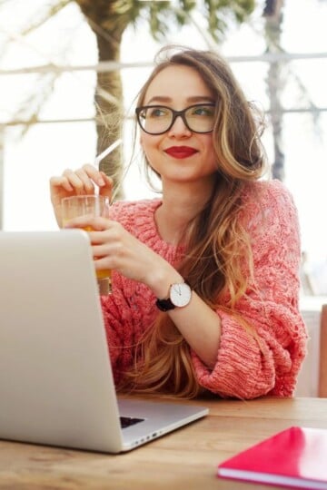 woman with red lipstick and iced coffee smiling