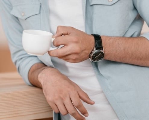 man who has everything leaning on counter with coffee and watch gift